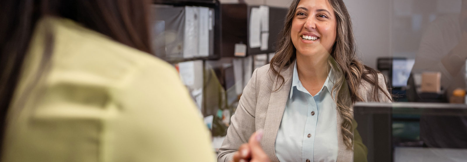 Woman talking to teller at bank.