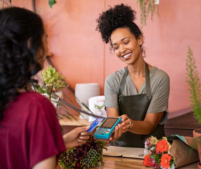 Woman paying with card at flower shop.