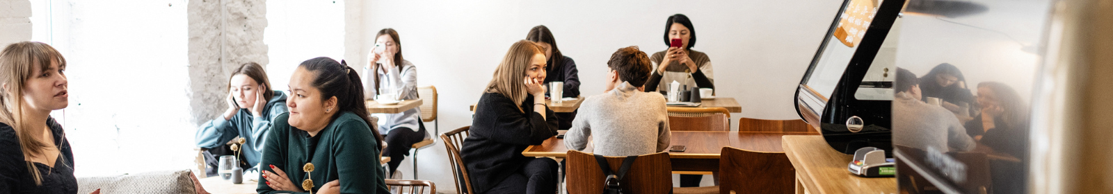 8 young people sitting around talking at a restaurant